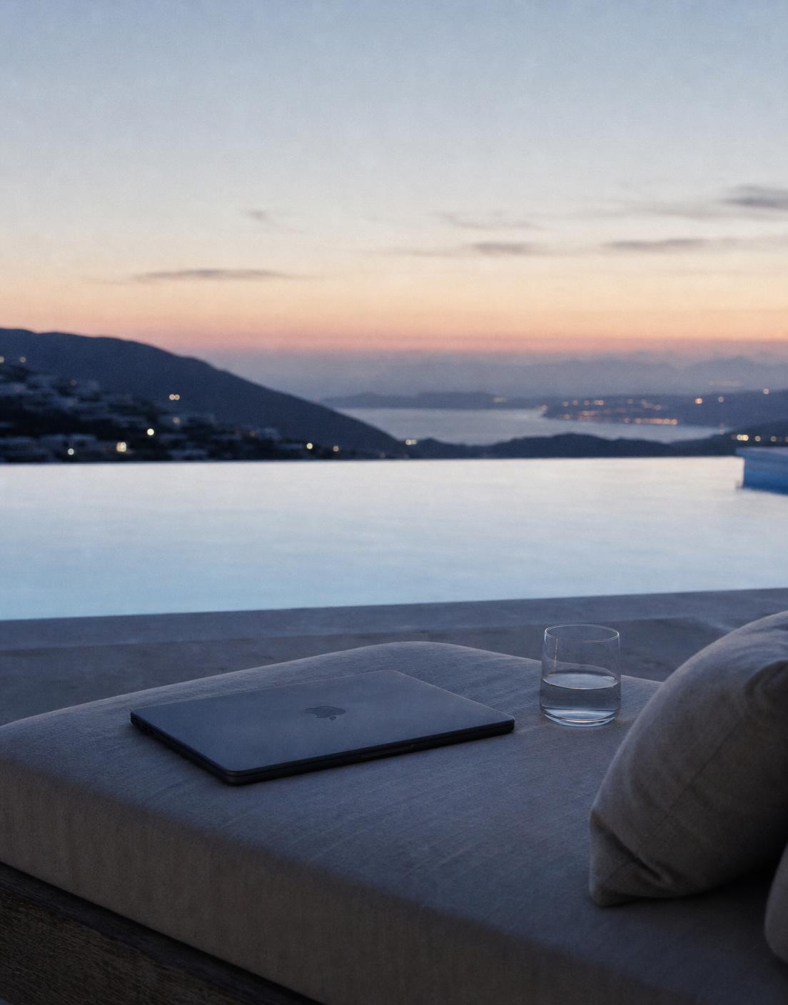 Infinity pool at dusk with a laptop on a lounge chair